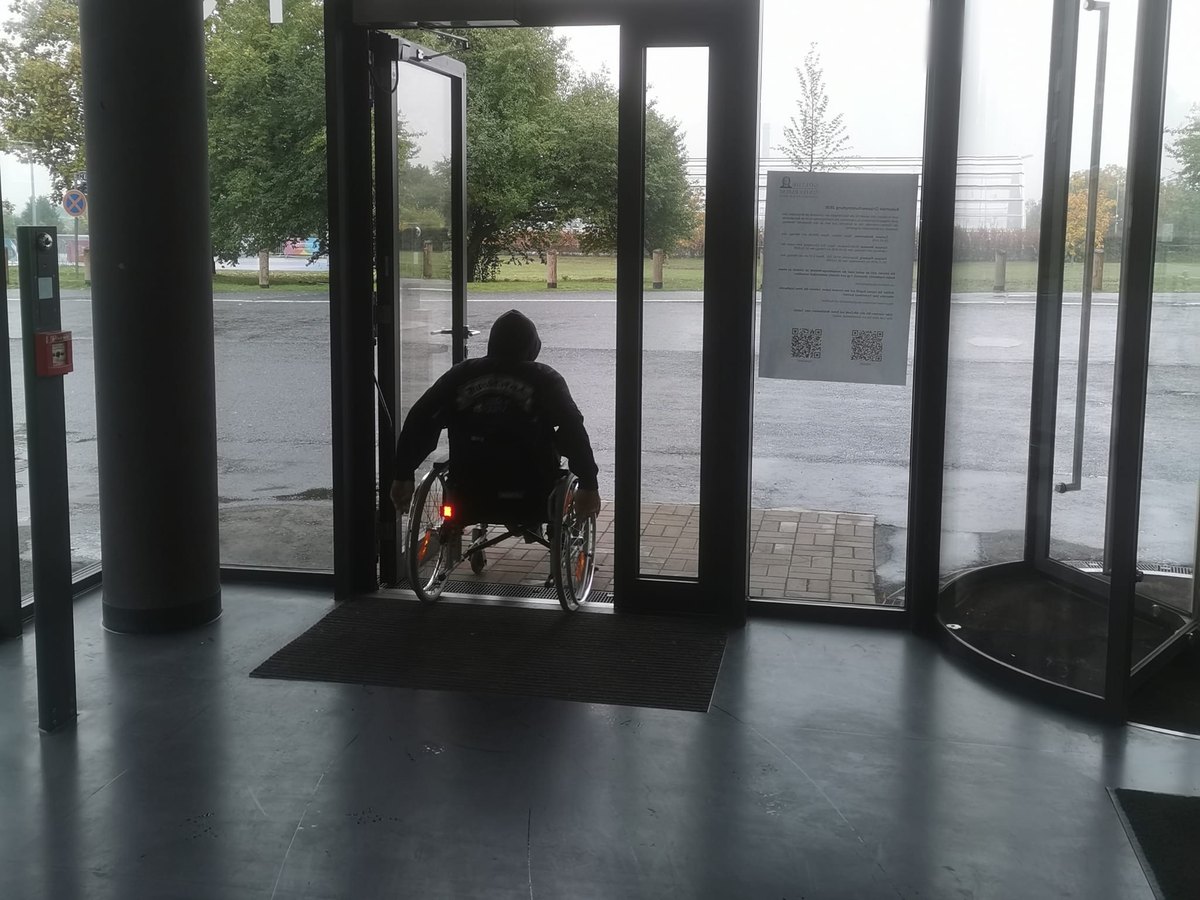 Rollstuhlfahrer passiert eine Tür mit Antrieb und schwellenlosem Übergang